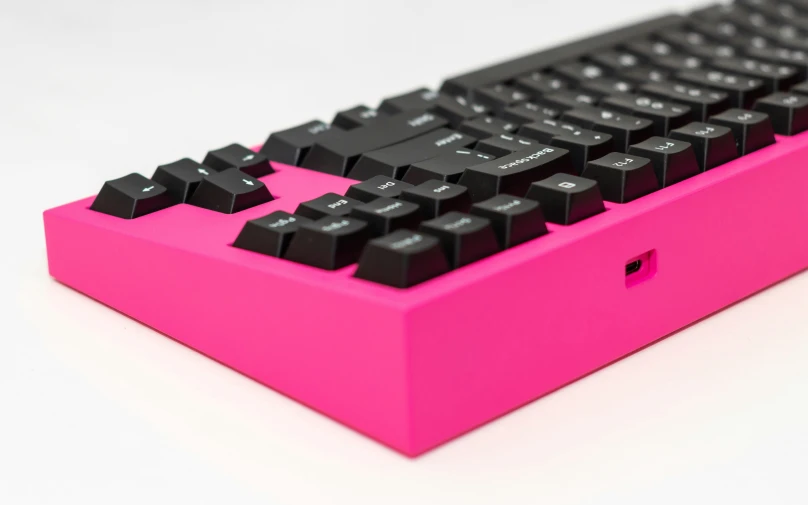 a pink computer keyboard that is sitting on the table