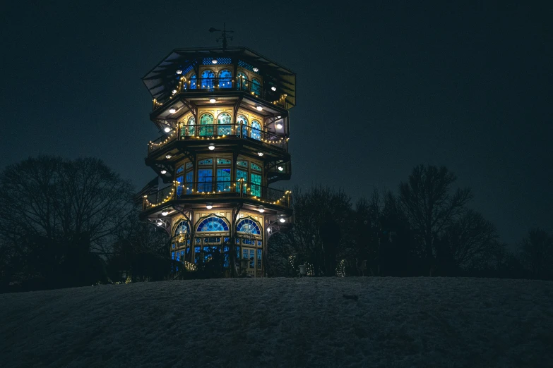 a night view of a lighted tower that is sitting above a hill