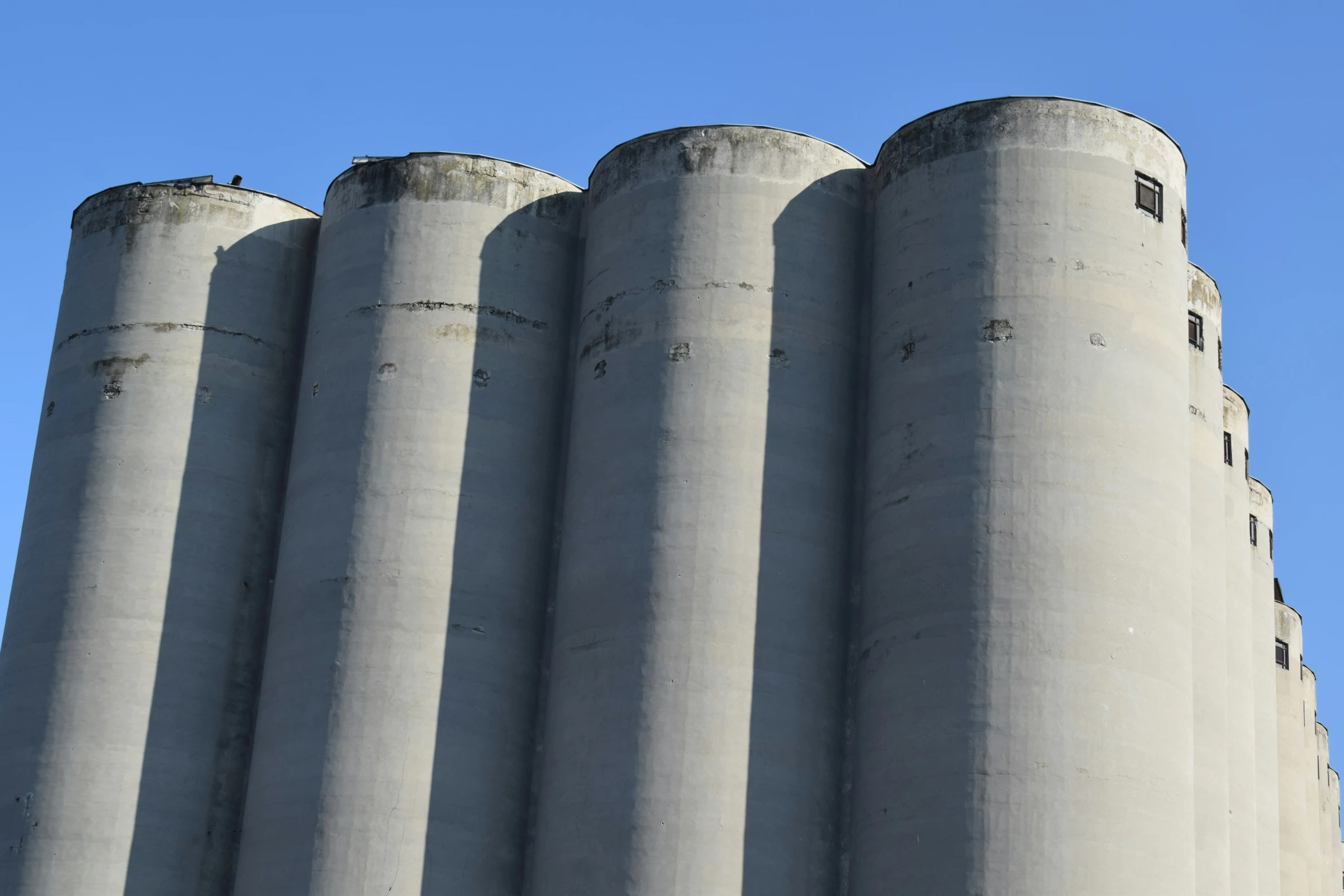 three tall silos with one bird perched on one
