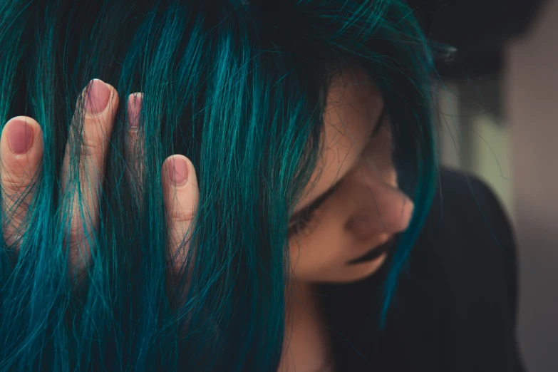 a girl with green and blue hair, showing her hands over her face