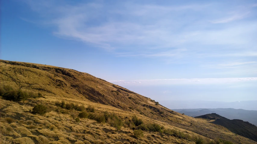 a man on a mountain top with the blue sky above