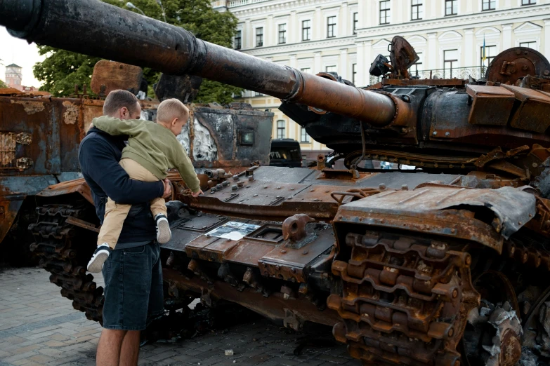 a couple looking at some old tanks in front of a building