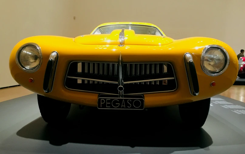 a vintage yellow sports car on display in a museum