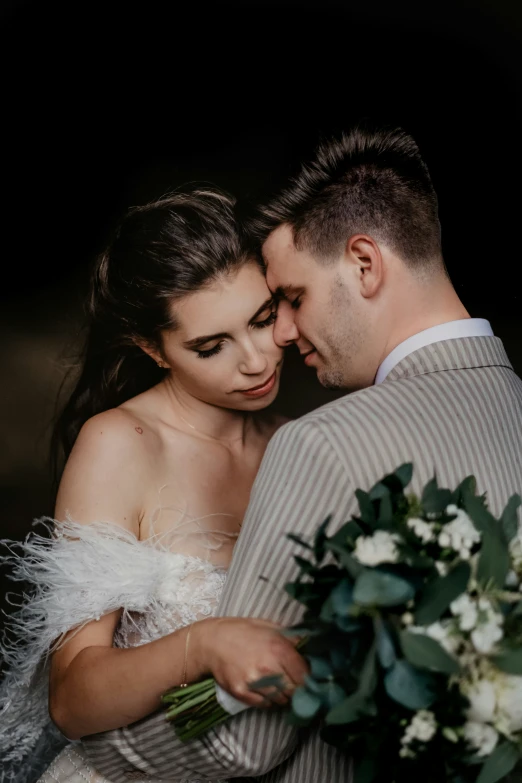 man and woman in formal dress standing next to each other holding a bouquet