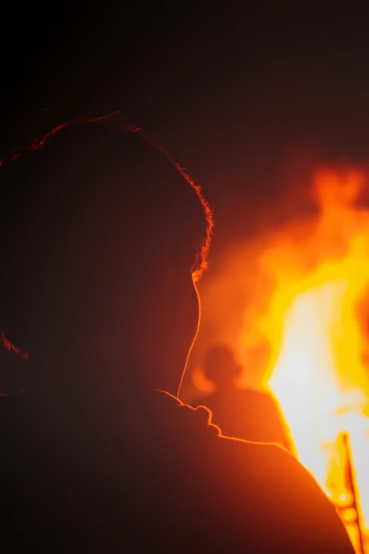 a close up of a person standing in front of a fire