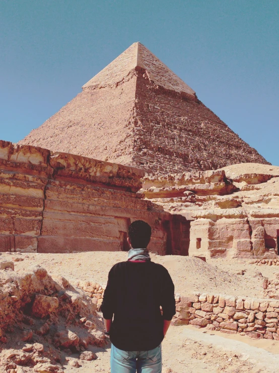 a man stands in front of a large pyramid