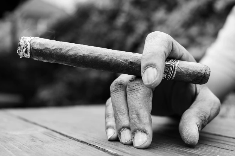 a hand is holding an cigar over a wooden surface