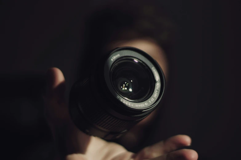 a person holding up a large lens to take a picture