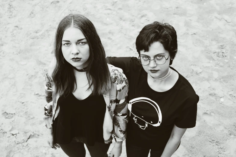 two women standing next to each other in front of sand