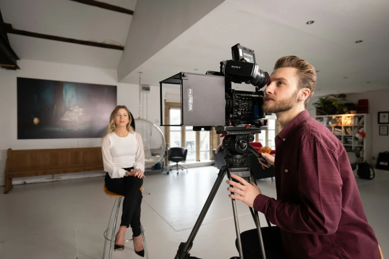 a man and woman are filming in a modern living room