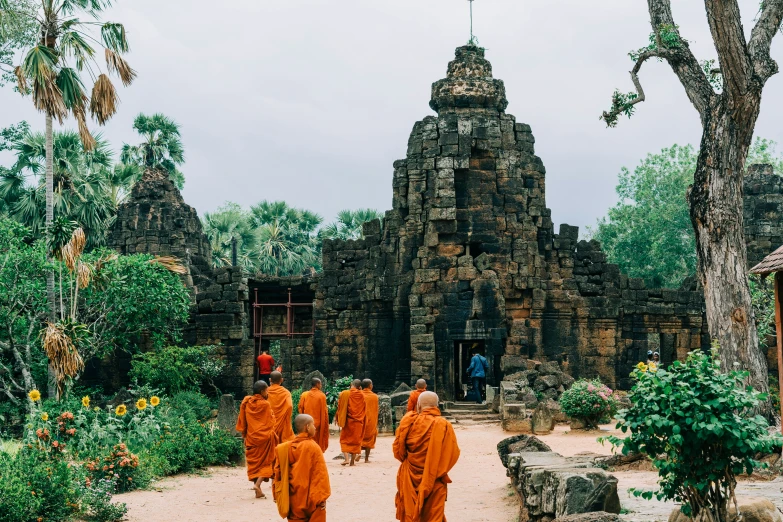 a group of monks walking across a dirt field