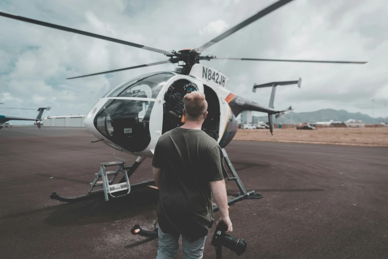 the man is waiting near the helicopter to take off