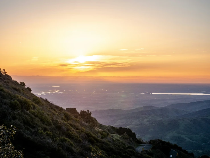 two people stand on a cliff watching the sun rise