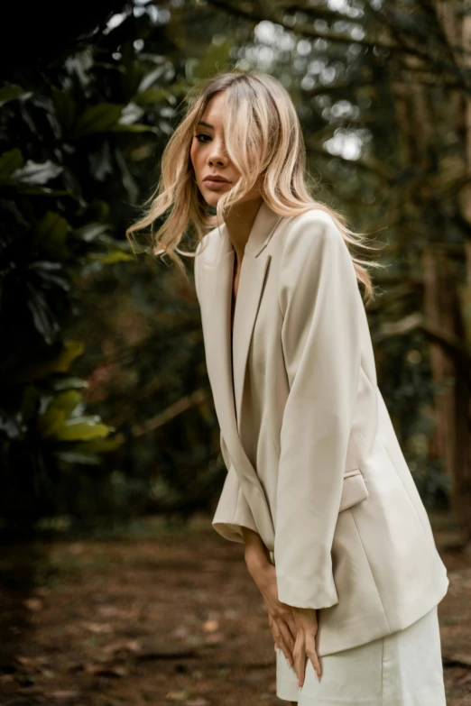 a woman in a white suit stands outside