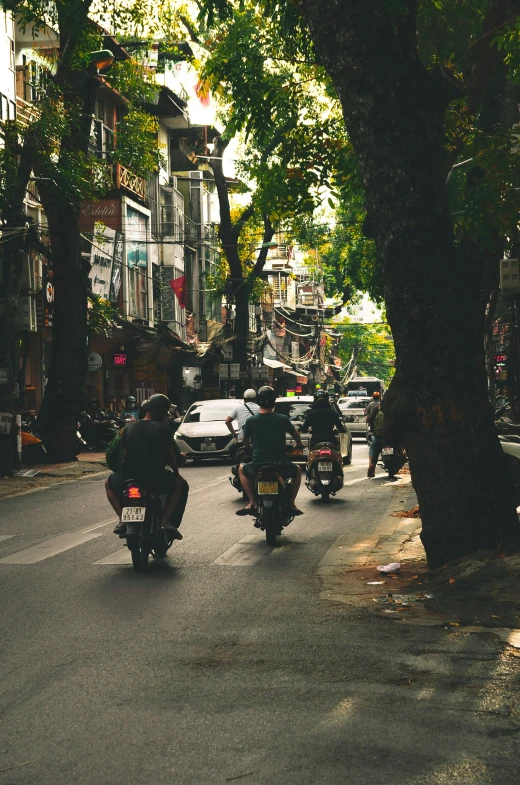 a man riding his motorcycle down a street while other motorcyclists ride by