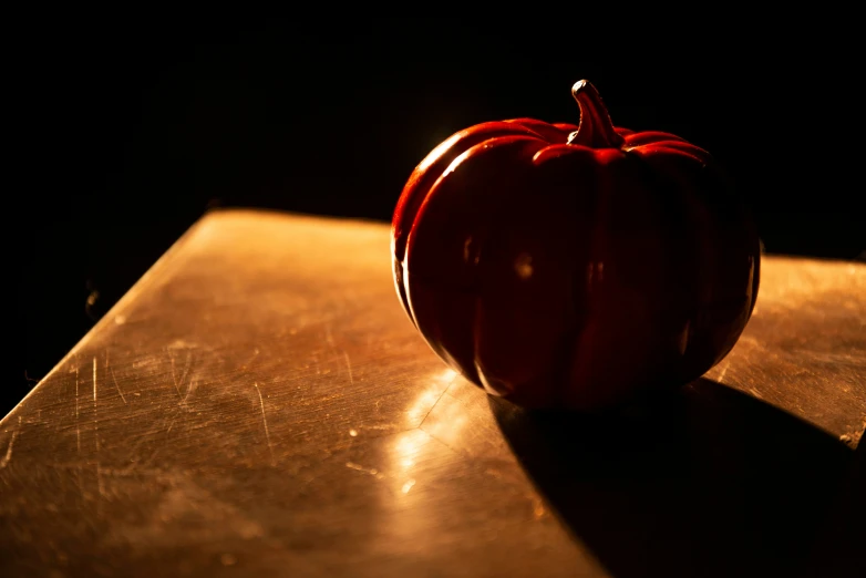 a red colored pumpkin sits on a surface