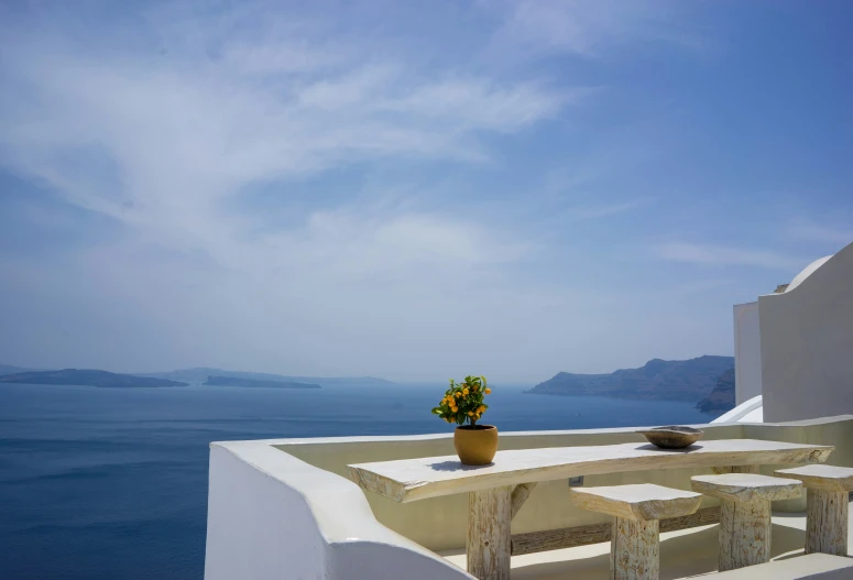 white table and chairs overlooking an ocean on a sunny day