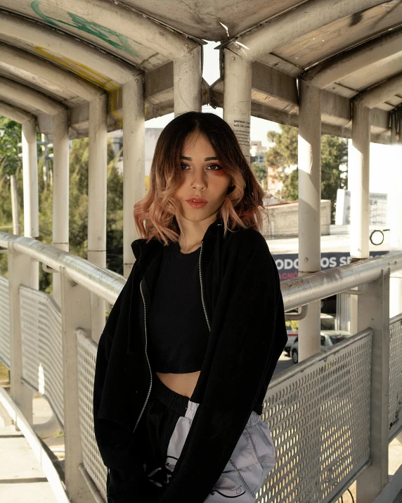 a beautiful young lady wearing a black jacket standing on a balcony