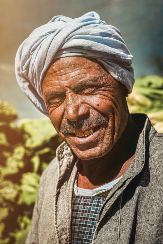 an older man with a head scarf on smiling