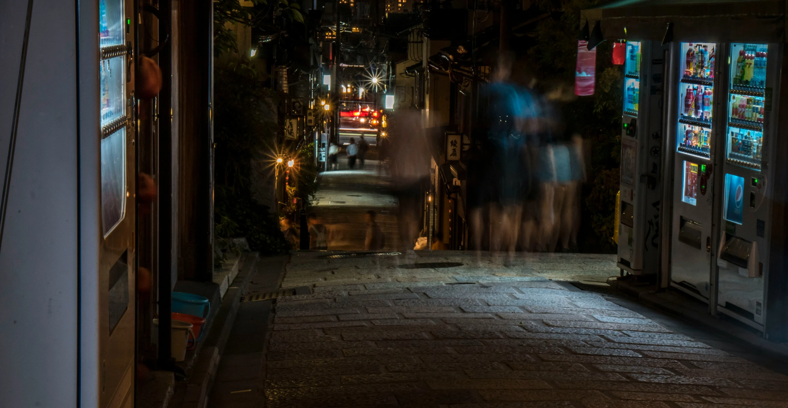 people in silhouette walk down a busy dark city street