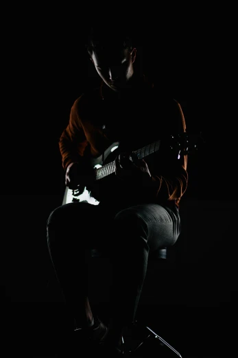 man kneeling down playing guitar with light on