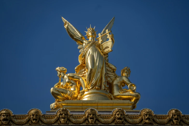 a gold statue sits atop a gold architectural feature