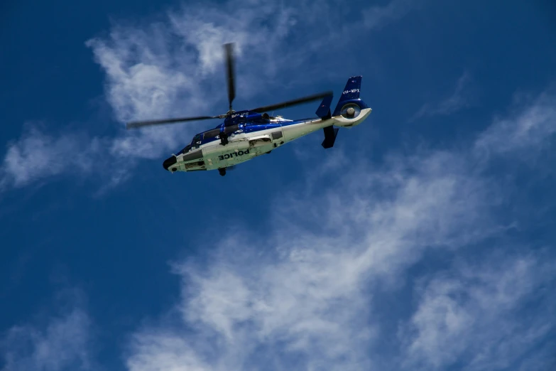 a blue and white helicopter is flying high up in the sky