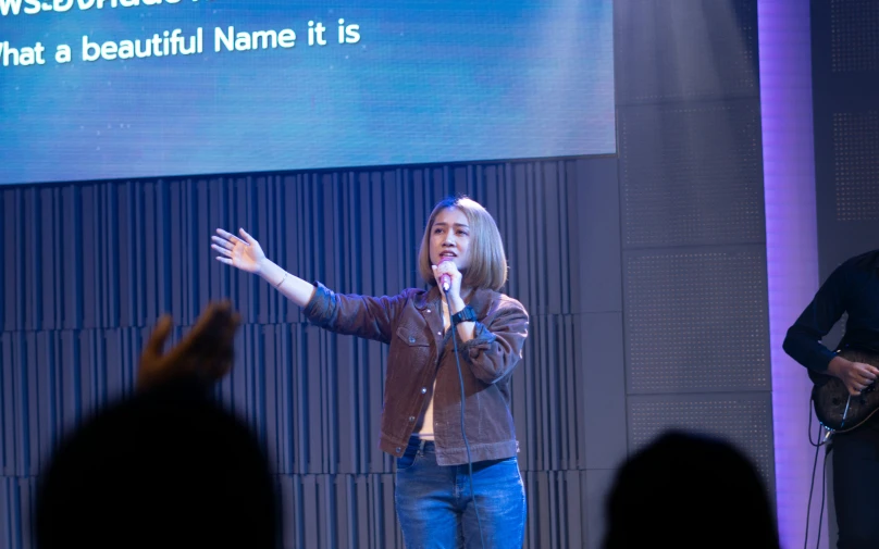 a woman stands at a microphone on stage in front of a crowd