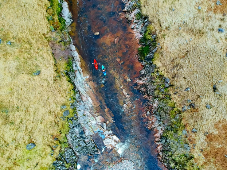 a road with red cars traveling next to a muddy river