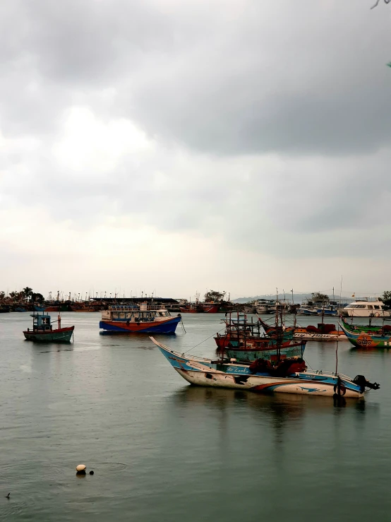 several boats floating in the sea on a cloudy day