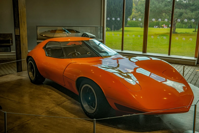 an orange sports car sitting in front of a window