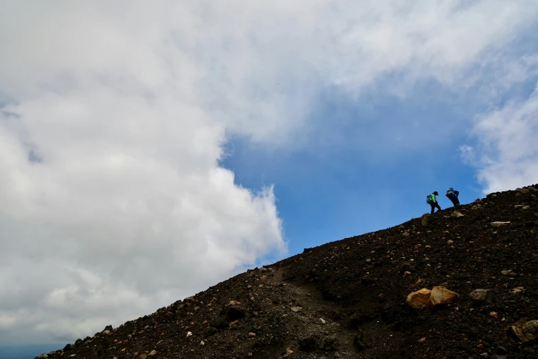 two people stand on top of a rocky mountain while holding hands