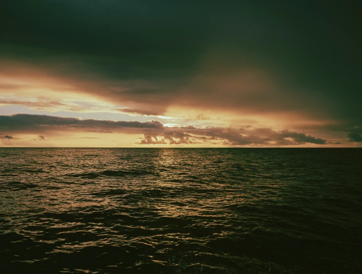 a beautiful sunset over some water on a beach