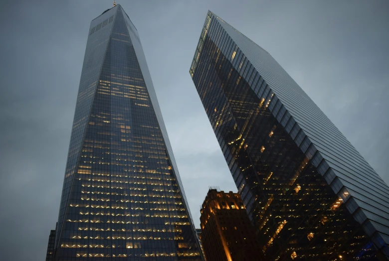 two skyscrs lit up in front of the sky