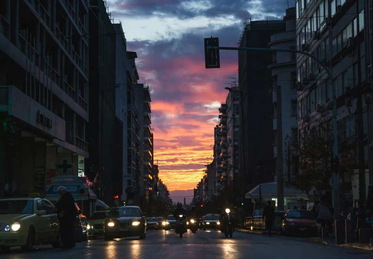 cars on a city street at dusk with clouds