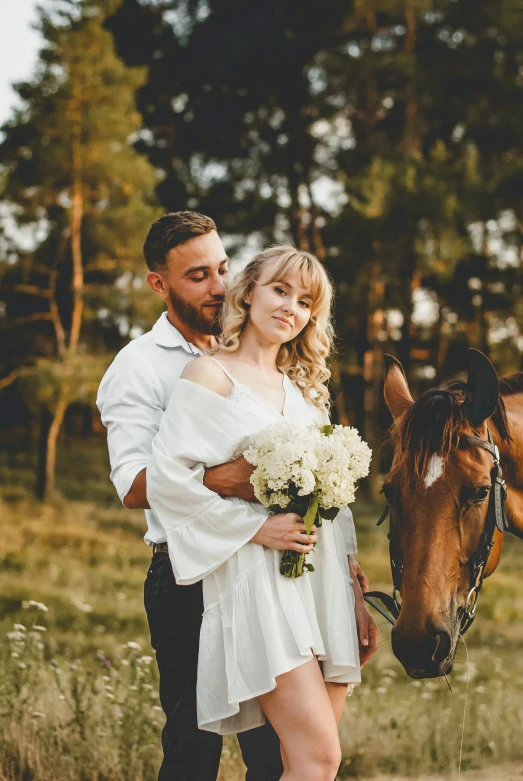 a young man standing next to a girl near a horse