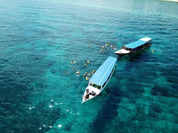 people are on boats in clear water and white sand