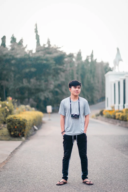 a young man is standing on an empty road in front of a church