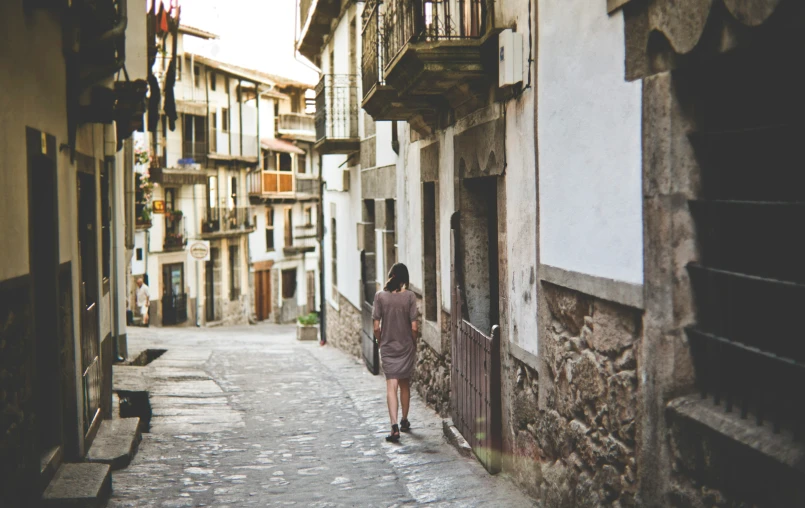 a person standing in an alleyway with buildings