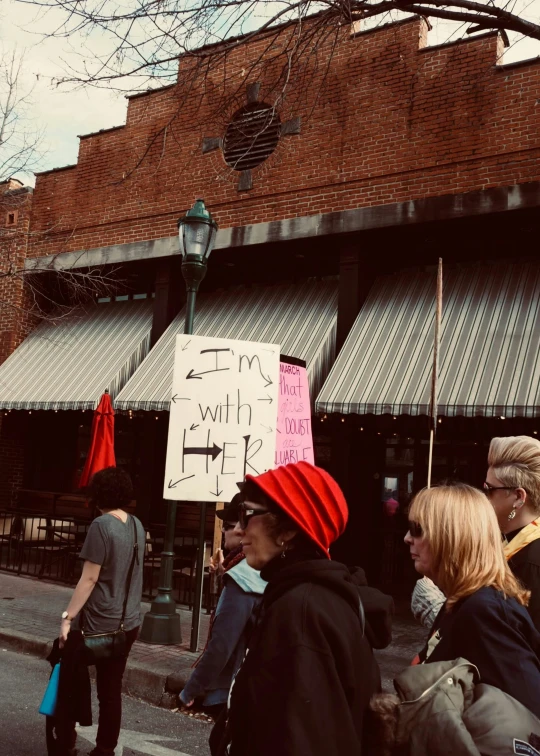 a person with a sign standing on the side of a street