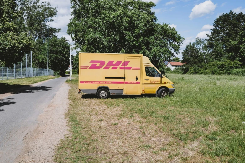 a delivery truck is parked on a field by some trees