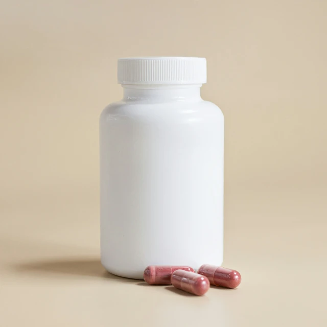 pills in white bottle sit on a beige surface