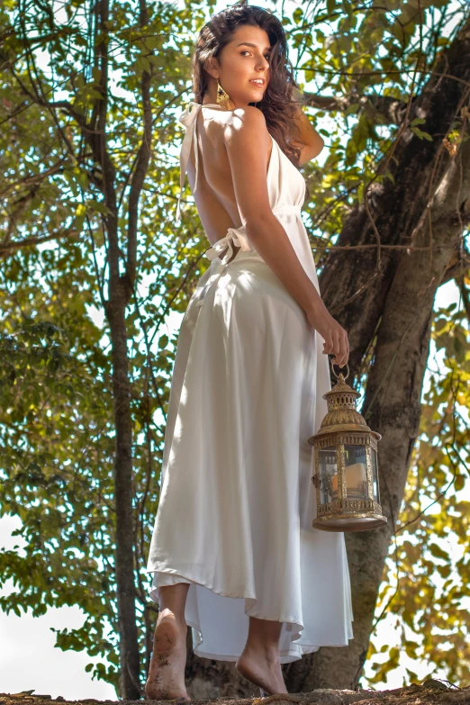 a woman standing on top of a tree nch next to a lamp