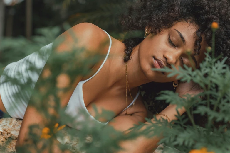 a young woman laying down wearing a white tank top