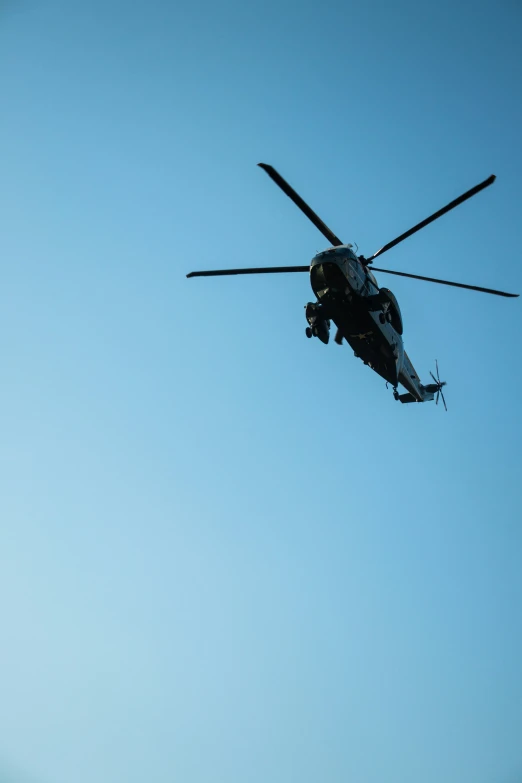 a helicopter flying through a blue sky in the day