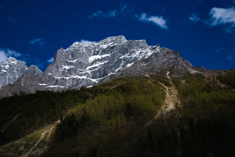 a snow capped mountain with a trail in the foreground