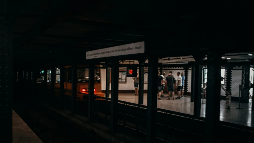 a train is pulling into the station where people stand