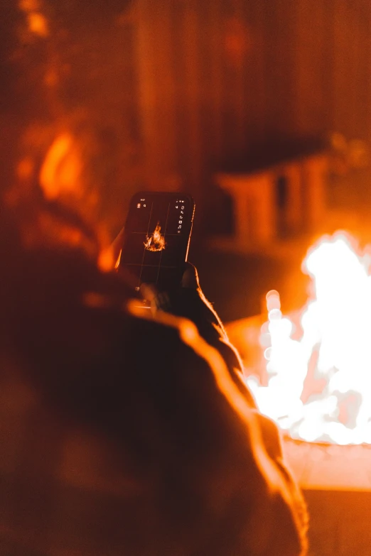 someone pointing their phone in front of a fire