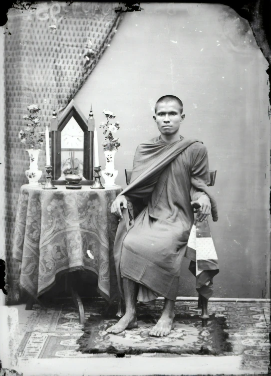 a man dressed in a robe and sitting at a table with a clock and candle