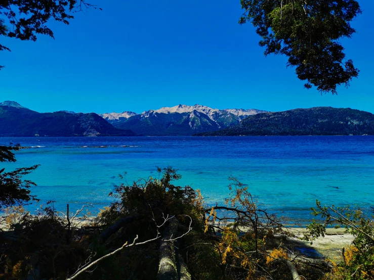 the mountains are beyond a beach and clear blue water